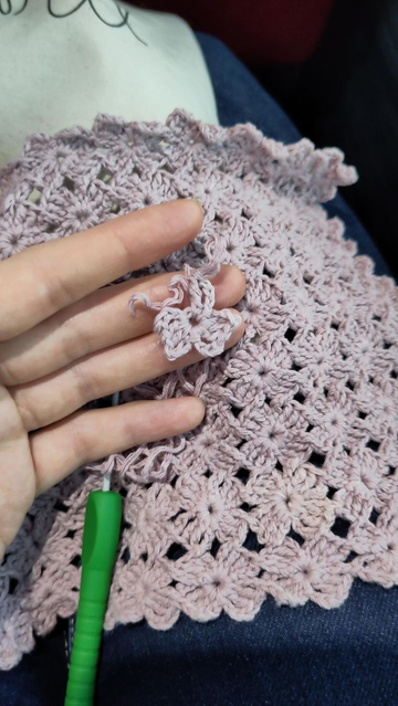 Small crochet flower in a shade of pink, in the background you can see the flowers form a solid piece.