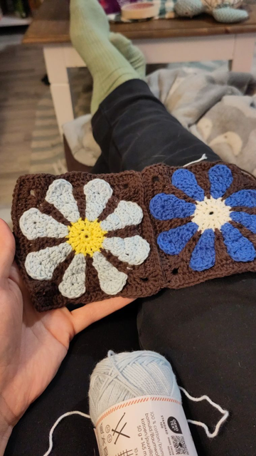 Crochet flower squares. The petals are different shades of blue and the background is brown.