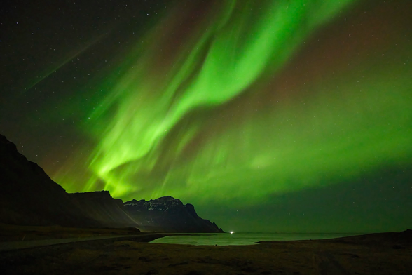 Aurora Borealis over water and mountains. 