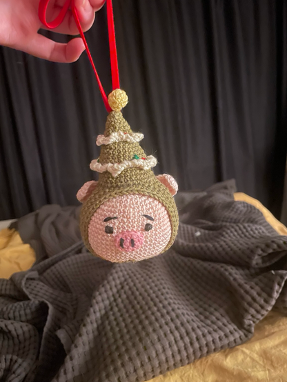 A crocheted pighead wearing a Christmas tree as a hat 