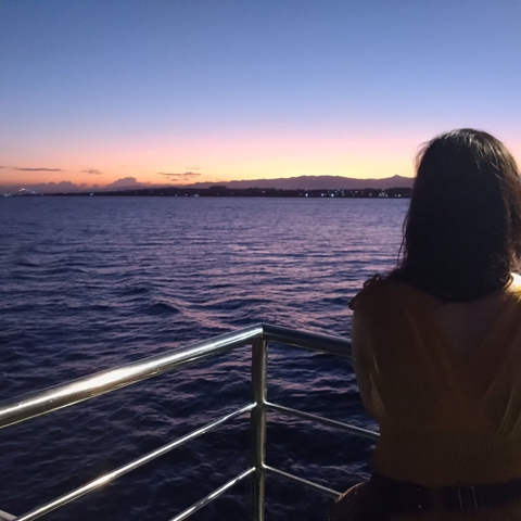 Image of woman in yellow dress looking out over the bow of a ship in the Philippines.