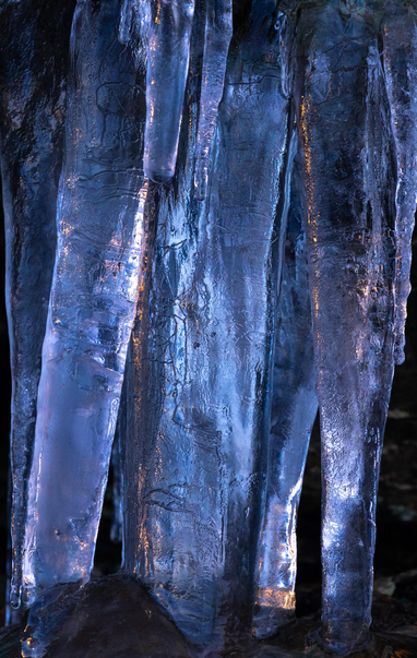 Sunlit long icicles. A mix of blue and orange.