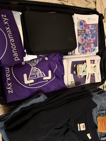 Photo d'une valise ouverte avec des flyers, stickers, gilets au logo Panoramax