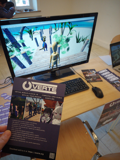 Photo of the game running on a desktop computer and a hand holding a leaflet.
