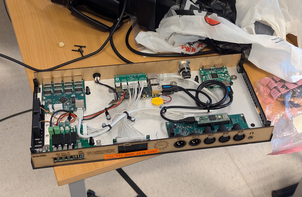 An open box made from lasercut wood panels. It shows lots of custom boards and cabling.