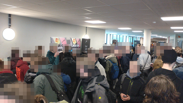 A packed hall of people with the Linux on Mobile stand in the background.