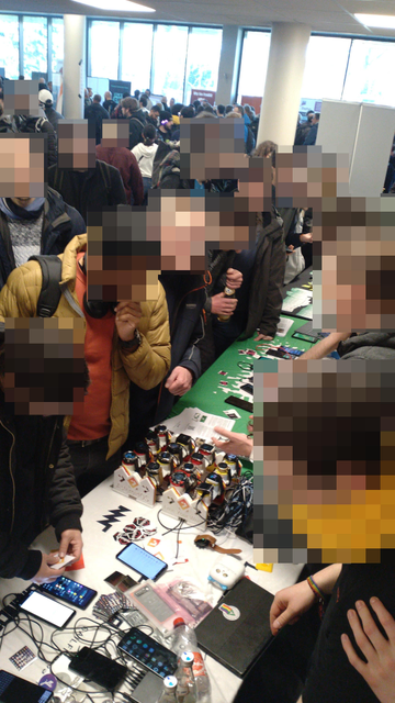 The stands from above, lots of people all around the stands, phones, a bank of watches and laptops strewn across the stand table top.