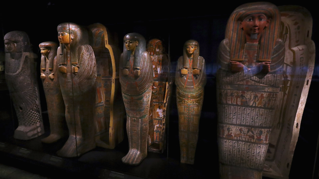 Queens of the Nile Exhibition at Rijksmuseum van Oudheden in the Netherlands. (Image credit: Photo by Dean Mouhtaropoulos via Getty Images): A row of intricately decorated ancient Egyptian sarcophagi, featuring vibrant painted designs and hieroglyphs, displayed in a dimly lit museum exhibit.