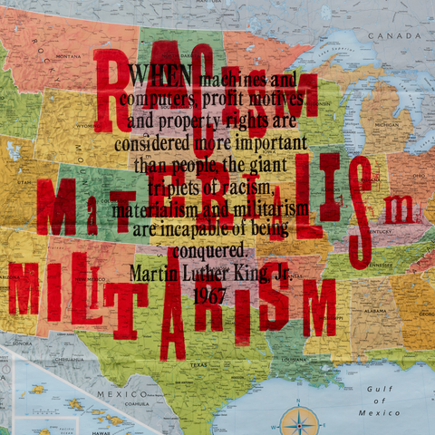 Letterpress type printed over the top of a U.S. map. The words “RACISM, MATERIALISM, MILITARISM” are in red. A quote from Martin Luther King, Jr. from 1967 is in black: “When machines and computers, profit motives and property rights are considered more important than people, the giant triplets of racism, materialism and militarism are incapable of being conquered.”