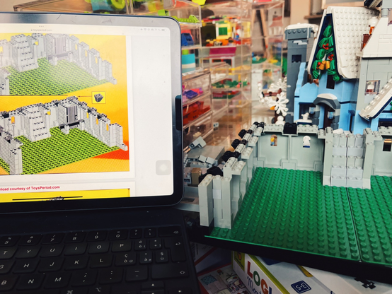 a photo showing a vintage LEGO manual displayed on an iPad (on the left) showing instructions for building a castle. On the right hand side you can see the real set being built by me... and in the background there is the set from Santa's Visit