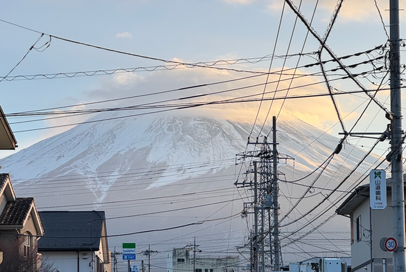 A tangle of power lines on a street facing Mt. Fuji