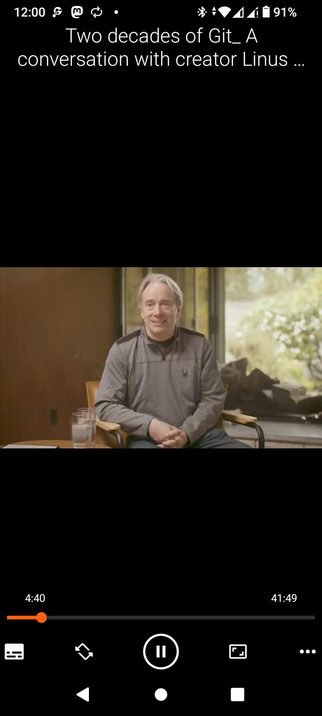 The screencap showcases a VLC video player interface on an Android with a video titled "Two decades of Git: A conversation with creator Linus..." The video is currently at 4:40 out of a total duration of 41:49. The video features a man Linus Torvalds sitting in a chair, wearing a gray long-sleeve shirt with a small logo on the left side, and dark pants. He is seated in front of a large window with a view of greenery outside. There are two glasses of water on a small table to his left. The background includes a wooden wall and a large window, suggesting an indoor setting with natural light. The video player interface includes standard controls such as play, pause, and volume adjustment, along with a progress bar indicating the current playback position.

 Ovis2-8B

🌱 Energy used: 0.187 Wh