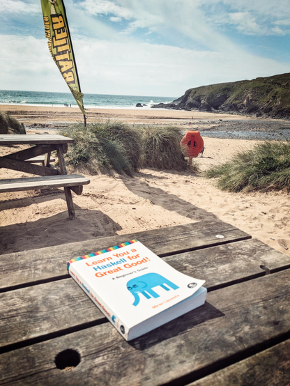 Book Learn You a Haskell for Great Good on a bench amongst sand on a sunny beach 