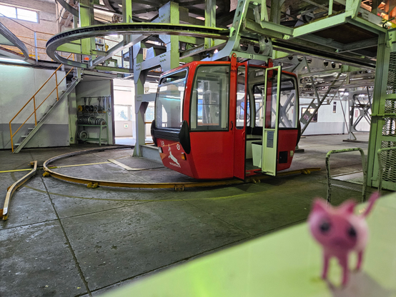 A blurry p-chan on a handrail in front of a gondola that's waiting for people to board.