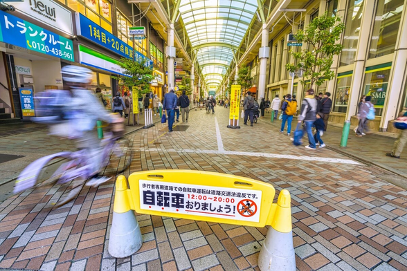 Person running bike into an area with a sign that reads "Please dismount from your bikes"