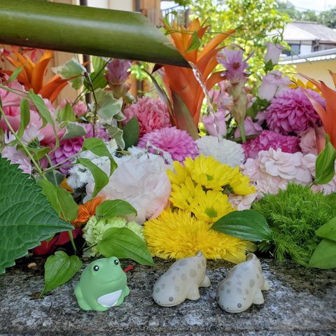 A frog and salamanders (fortune holders) sit on the rim of a beautifully decorated water basin (filled with flowers).