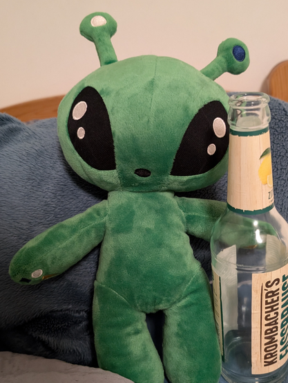 the ikea alien plushie posing with a bottle of fassbrause 