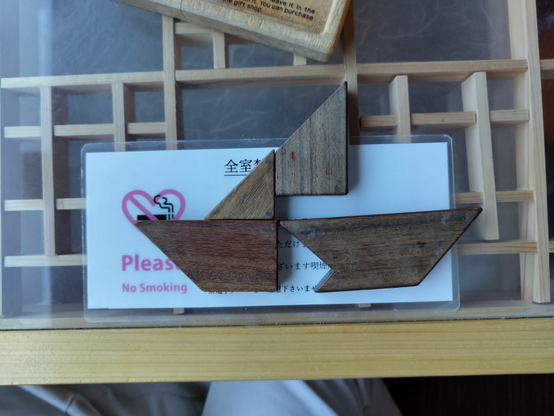 Wooden puzzle assembled in the shape of a simple boat. some connecting parts of the boat are simply missing.
