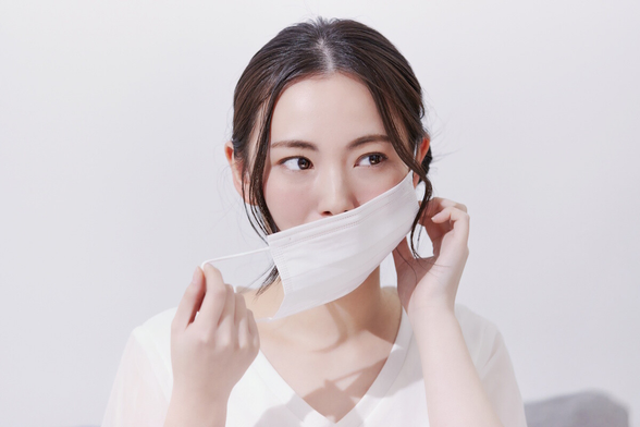 Young woman putting mask on her face