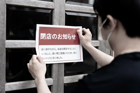 Man putting a "Store Closed" sign on a storefront