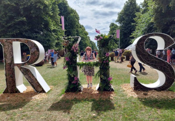 Mandy at RHS Hampton Court hiding behing huge RHS letters 