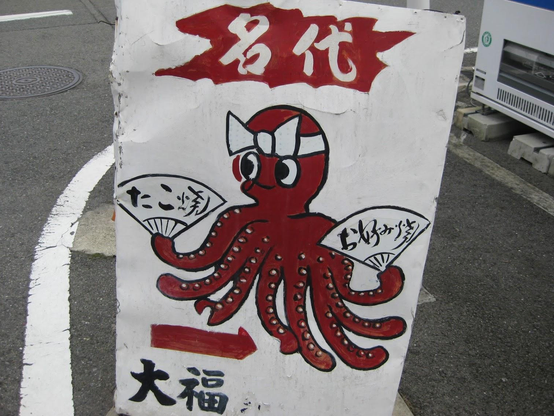 An octopus sign guides visitors to a takoyaki shop.