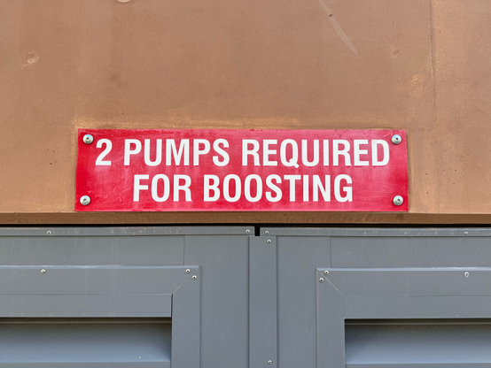 A red sign with white writing that says “2 Pumps required for boosting” in all caps. 