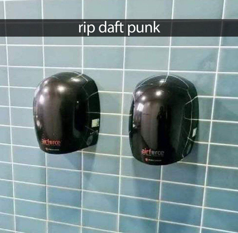 A light blue bathroom wall with two mounted hand soap dispensers that are all black and look like… helmets