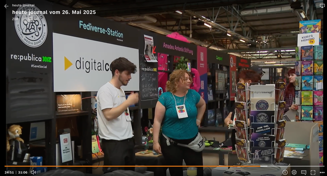 Zu sehen ist der Messestand von Digitalcourage auf der re:publica 2025, klar erkennbar an der großen „Fediverse-Station“-Beschriftung und dem bekannten Logo. Der Stand ist gut besucht, im Vordergrund steht ein Aufsteller mit der „Kurz & Mündig“-Reihe, daneben Infomaterial mit dem Slogan „Join the Rebellion“. Im Hintergrund: weitere zivilgesellschaftliche Organisationen wie die Amadeu Antonio Stiftung und Campact. Der Beitrag stammt aus dem ZDF heute journal vom 26. Mai 2025.