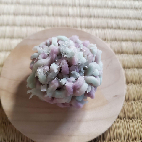 A kinton (a traditional Japanese sweet made from shredded yam dough about a bean paste ball) coloured shades of purple to mimic a hydrangea flower speckled with dew.