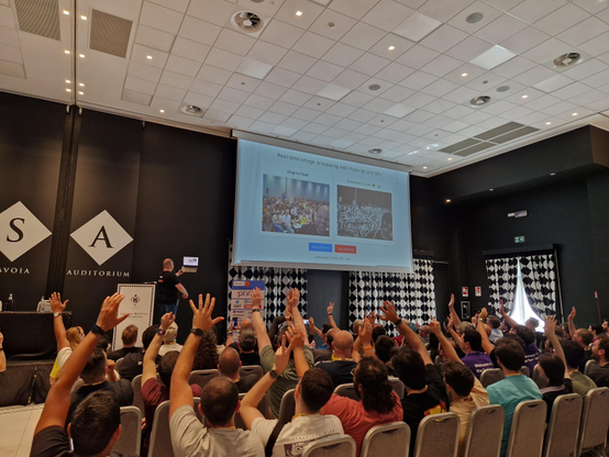 Antonio on stage, taking a selfie of himself and the audience, at the same time showing his webcam image on the screen along with a processed-outline version, running at 60fps with SPy. 