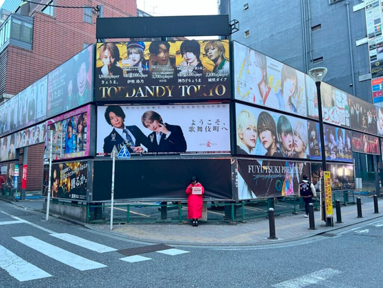 Wman standing in front of a series of host club billboards in Kabukicho