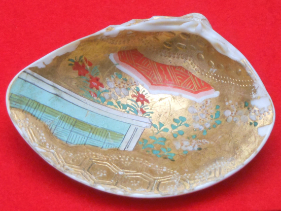 Close up of a shell painted with a scene from The Tale of Genji.