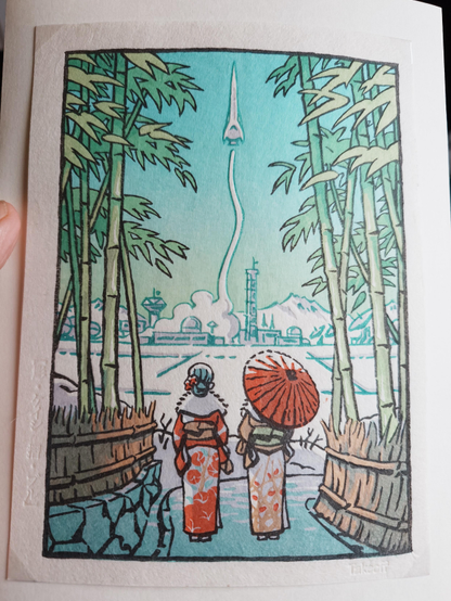 Holzschnittdruck im japanischen Stil. Zwei Frauen im Kimono in Rückansicht blicken von einem mit Bambus gesäumten Weg auf eine weite, schneebedeckte Ebene. In der Ferne sieht man einige Gebäude, offenbar eine Raketenabschußbasis. Eine Rakete im retrofuturistischen Design steigt gerade in den Himmel. 