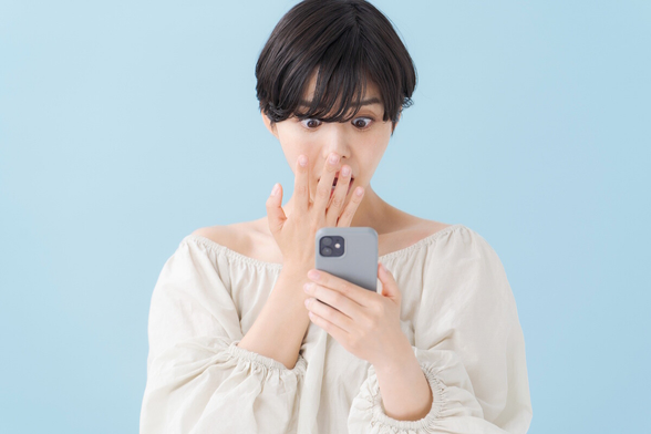 Woman looking at her phone in shock and horror