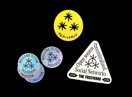 Set of stickers with the asterism symbol, representing the fediverse. One is yellow, another is silver, and the last one is black on white.