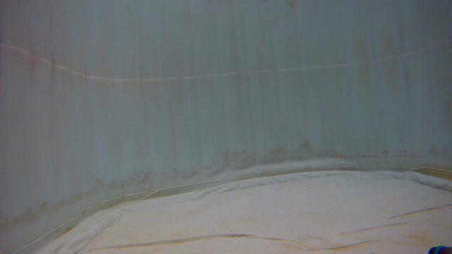 A wide shot underwater in a stained white tank/pool. A small submersible with cute LED lights on it rises into frame from the bottom right hand corner. It then thrusts across the screen to top left corner gaining altitude as it goes. 