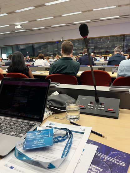 Conference Room of the European Commission, a desk with a laptop, a microphone and a lanyard.