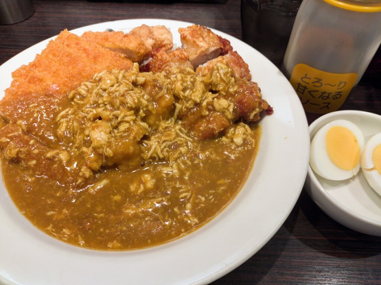 ココイチの店内にて、甘口ポークカレー200gにチキンにこみ、チキンカツ、パリパリチキン、フライドチキン3個をトッピング。皿の右手にはゆで玉子の小皿と甘くなるソースのボトル。