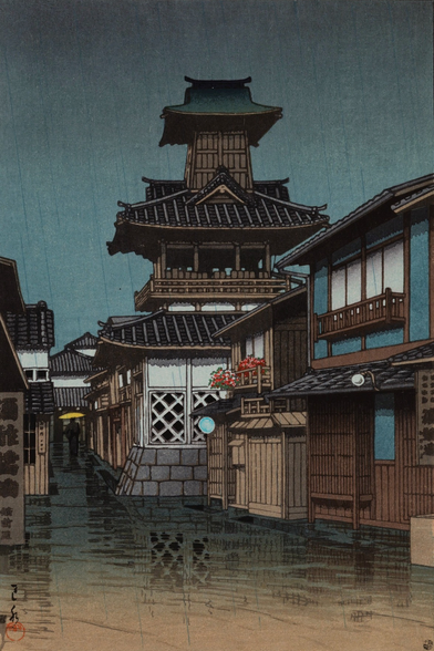Rain falls on a quiet street somewhere in Okayama, Japan. On our right, the windows of houses are shut; pots of flowers sit out on a narrow second-story balcony and an adjacent rooftop, catching the rain. Up ahead, a temple bell tower stands tall against an overcast sky. Further on, as the street narrows to the width of a little lane, a single figure carries a yellow umbrella over their head as they walk away from us. In the foreground, the rain-slicked street reflects the scene.