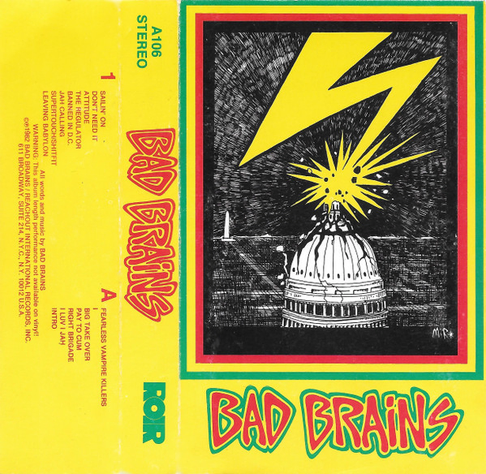 A scan of the cassette J-card. The cover art is a drawing by Donna Lee Parsons of the Capitol Building in Washington DC being struck by lightening, all in black ink except the large stylized lightening bolt in yellow. The drawing is surrounded by 3 borders, in red, yellow, and green, with the Bad Brains logo also in the 3 colours, against a yellow background. The rest of the J-card is also on a yellow background, with the band logo in red and the label local in green on the spine, and the track list in small red font.