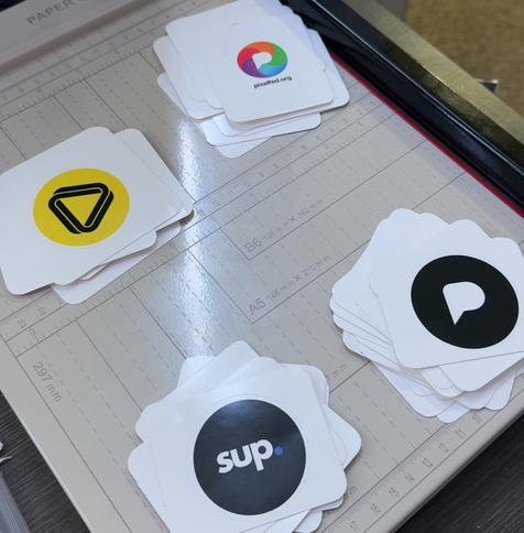 Image of a stack of recently chopped and rounded stickers of Pixelfed, Loops and Sup