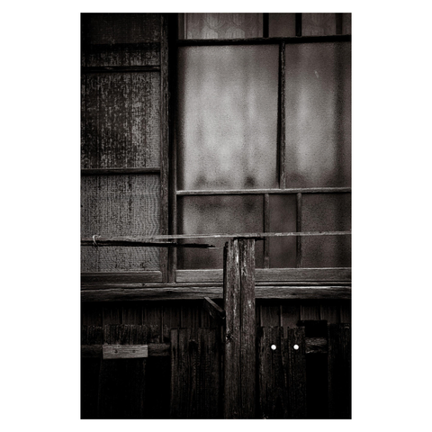A close-up of an old window and wooden fence, weathered and patched together over the years. The frosted glass softens whatever lies beyond, while the slats of wood below show signs of countless repairs.
