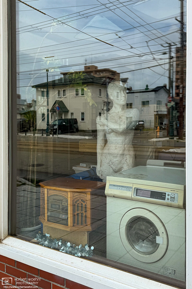 Shot into the window of a used-goods store in Hakodate, Japan, with a rather eclectic inventory of vintage household electrics and a white statue.