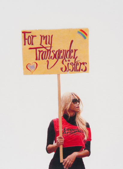Drawing against a white background of a blonde woman wearing sunglasses holding a yellow sign that reads "For my Transgender Sisters".