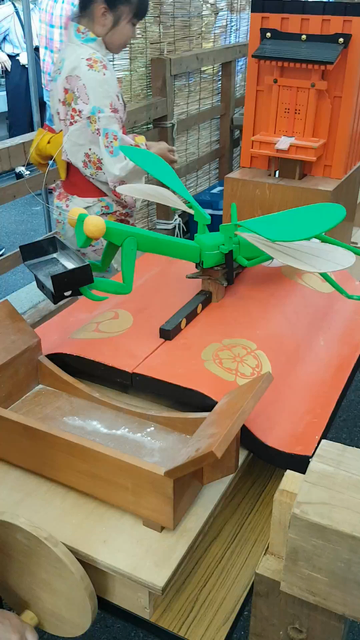 A mechanical praying mantis picks up and delivers fortunes at the Toro-yama float.
