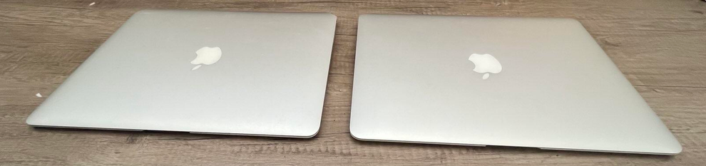 2 macbook airs lying flat and closed on a table. you can see the apple logos