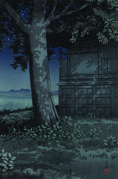 A moonlit view of the lakeside on a clear evening. In the foreground, a tall tree stands next to a darkened wooden building; beyond, the calm surface of Hachirogata Lake stretches out toward a shadowy, mountainous horizon. Above, stars shine in a clear sky. The scene is illuminated by the cold light of an unseen moon, shining somewhere above and behind the observer's viewpoint.