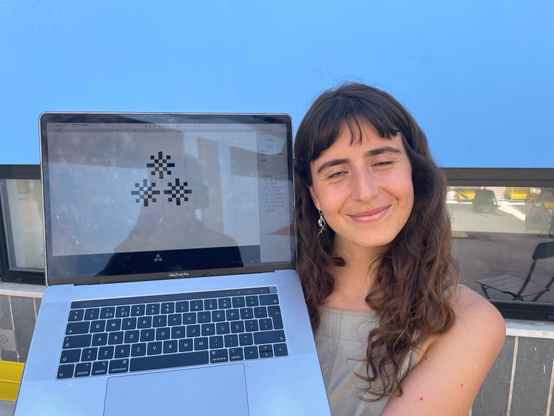 Sofia showing the screen of her MacBook with the Glyphs software open, and the asterism glyph she designed displayed