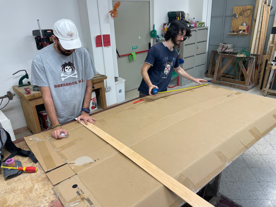 Maurizio and Pietro measuring the cardboard in order to cut it so that it matches my height.